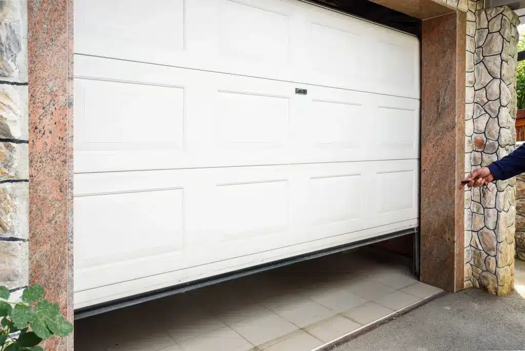 Benefits of Insulating Your Garage Door White electric garage door opening with remote control in residential driveway