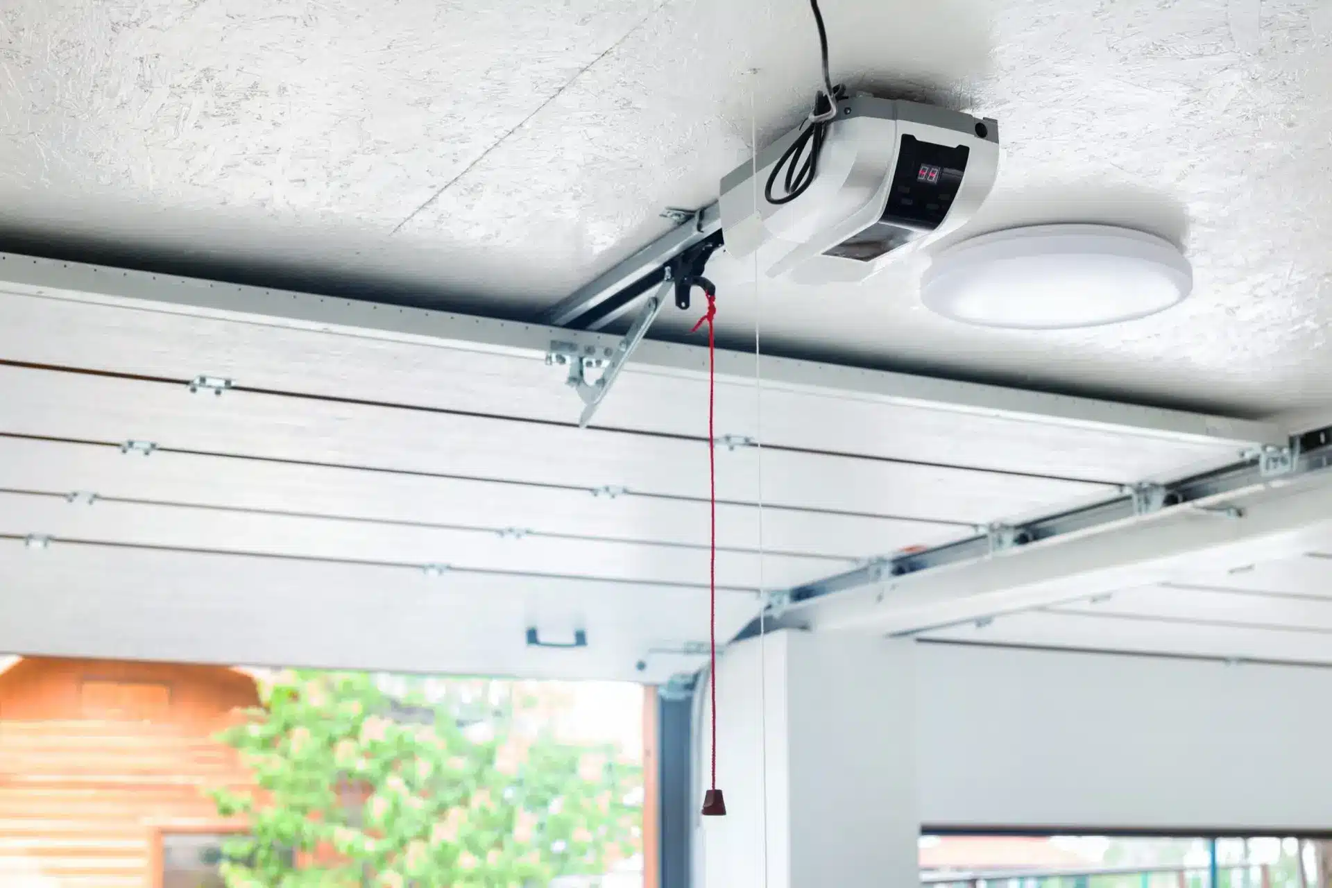 Ceiling-mounted garage door opener system with emergency release cord