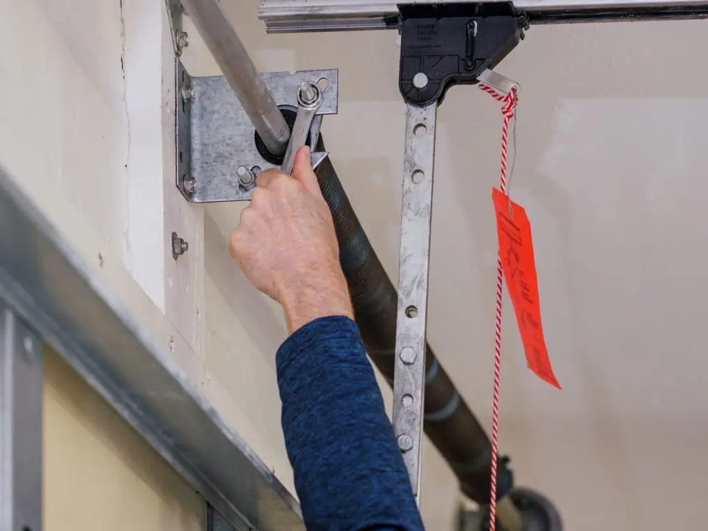 Close-up of technician adjusting torsion spring on residential garage door